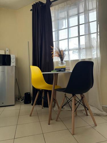 uma mesa de jantar com 2 cadeiras e uma janela em Ample Residence em Nairobi