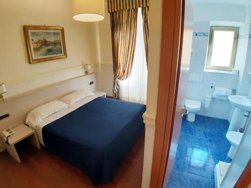 a bedroom with a blue bed and a bathroom at Hotel Mariano in Rome
