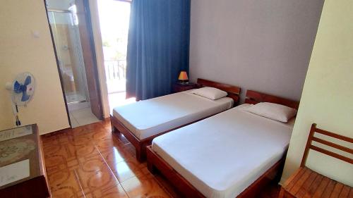 two beds in a small room with a window at Residencial Amarante in Mindelo