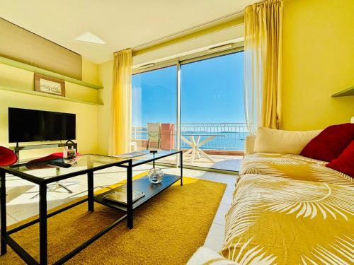 un salon avec un canapé et une grande fenêtre dans l'établissement Superbe appartement vue mer dans résidence avec piscine, à Théoule-sur-Mer