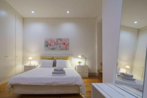 a bedroom with a large white bed and two lamps at Pink Street Apartment in Lisbon