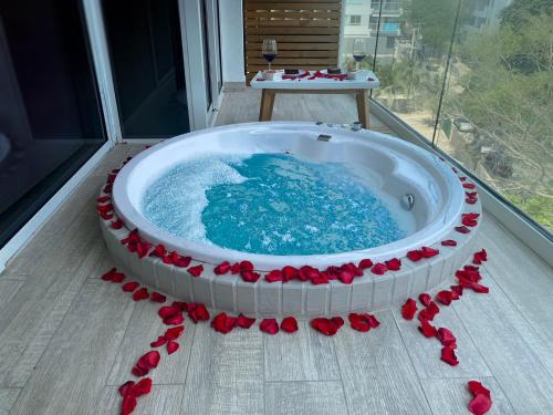 a hot tub with red roses around it on a balcony at Dominique Cartagena, Beautiful 2 Bedroom Apartment in Cartagena de Indias