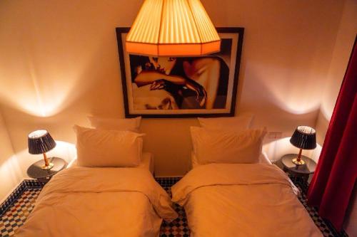 1 dormitorio con 2 camas, lámpara y foto en LUXURY apartment, en Marrakech