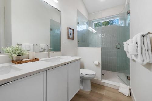 a white bathroom with a toilet and a glass shower at Sunset Cove 2 - Heated Pool - Sea Views - Walkable in Saint Augustine