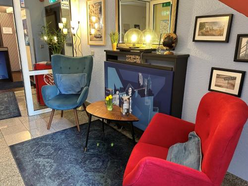 a living room with a red chair and a tv at Villa Hotel Frankfurt by MZ HotelCollection in Frankfurt