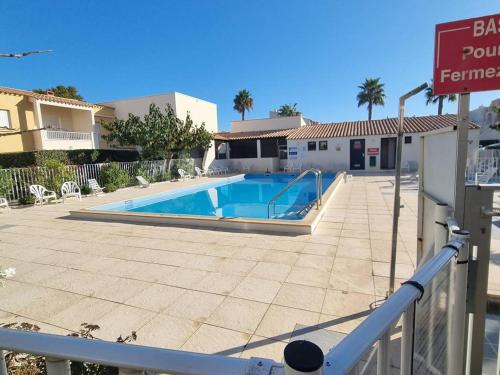 - une piscine en face d'un bâtiment avec un panneau dans l'établissement Appartement 4 pers, piscine, parking, climatisé, proche plage, salle de sport et commodités - FR-1-723-136, au Cap d'Agde