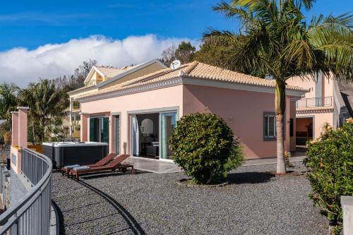 a small pink house with a palm tree at With jacuzzi sea view - Casa da Quinta Grande in Câmara de Lobos