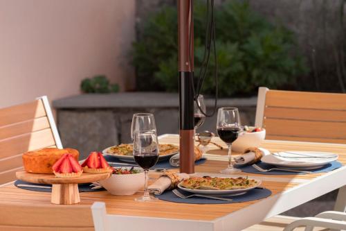 a table with plates of food and glasses of wine at Casa da Quinta Grande by An Island Apart in Câmara de Lobos