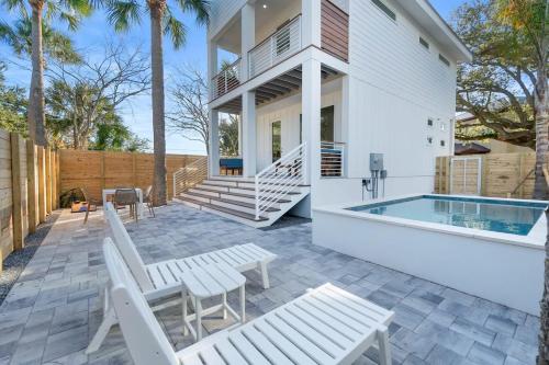 a patio with white chairs and a swimming pool at Sunset Cove - Heated Pool - Sea Views - Walkable in St. Augustine