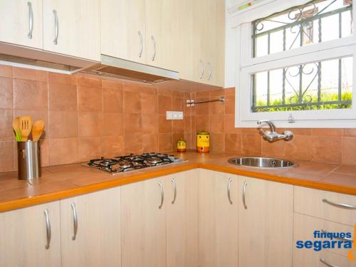 uma cozinha com armários brancos, um lavatório e uma janela em Casa Roda de Berà, 2 dormitorios, 6 personas - ES-320-19 em Roda de Bará