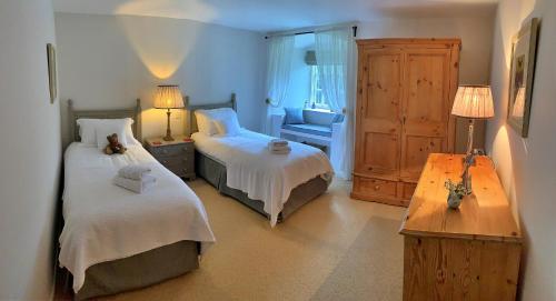 a bedroom with two beds and a chair and a table at Finest Retreats - Ingleby Manor - South Front in Great Ayton