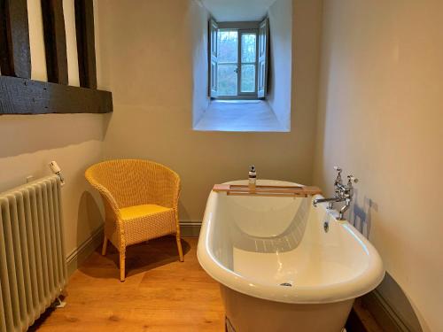 a bathroom with a tub and a chair and a window at Finest Retreats - Ingleby Manor - South Front in Great Ayton