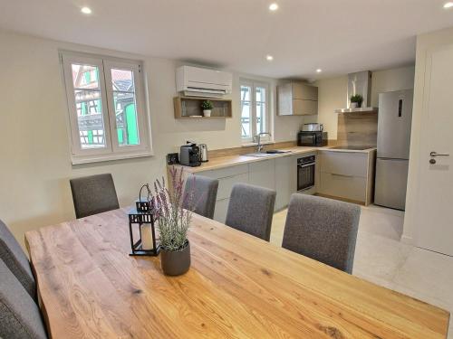 a kitchen and dining room with a wooden table and chairs at Maison rénovée avec 3 chambres, terrasse et parking, à 17 min de Strasbourg - FR-1-722-5 in Geispolsheim