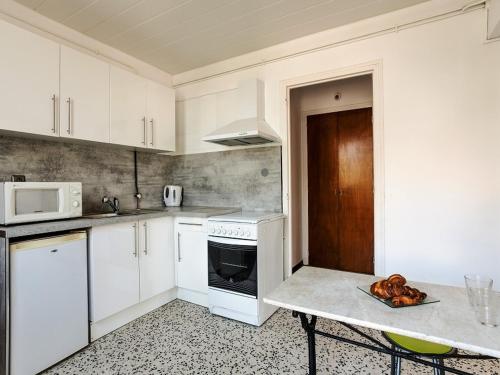 une cuisine avec des armoires blanches et une table à l'intérieur dans l'établissement Agréable T2 RDC avec terrasse, proche plage et commerces - FR-1-776-79, à Saint-Cyprien