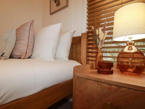 a bedroom with a bed and a lamp on a night stand at 1 Streamside in Looe