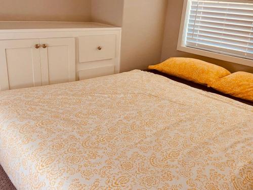 a bedroom with a bed with a yellow pillow and a window at Pinecraft Tiny Home 'Green Parrot ' in Sarasota