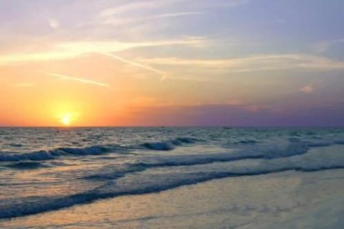 a sunset on the beach with the ocean at Pinecraft Tiny Home 'Green Parrot ' in Sarasota