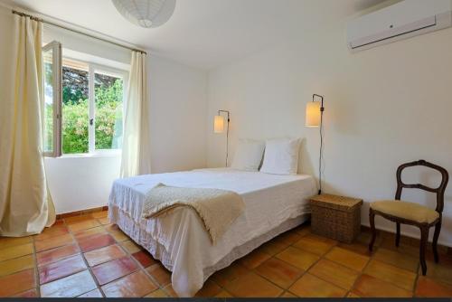 une chambre avec un lit, une chaise et une fenêtre dans l'établissement Elégante Villa avec piscine à Gassin - Villa Rose, à Fresnes-au-Mont