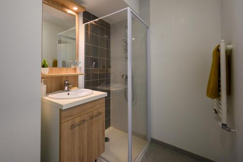 a bathroom with a sink and a shower with a glass door at Nemea Gières in Gières