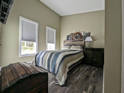 a bedroom with a bed with a wooden headboard and two windows at Captains Quarters by the Beach in Ellsworth
