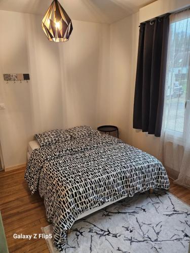Schlafzimmer mit einem Bett mit einer schwarzen und weißen Bettdecke in der Unterkunft Magnifique chambre in Beauvais