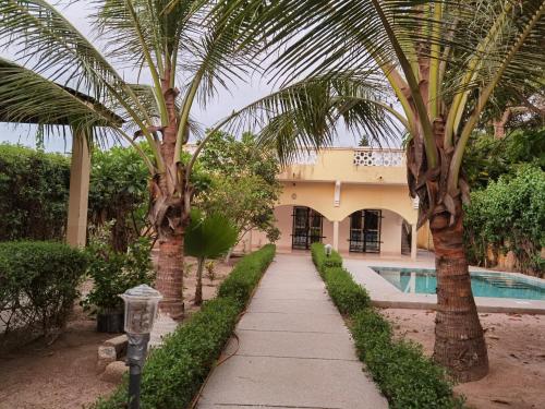 a walkway in front of a house with palm trees at Chez Sandrine in Ouoran