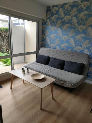 een woonkamer met een bed en een salontafel bij Appt RdC terrasse, 300m plage. in Courseulles-sur-Mer