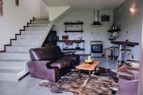 a living room with a leather couch and a staircase at Villa La Mercy Maisonette -No load shedding or water outage in La Mercy