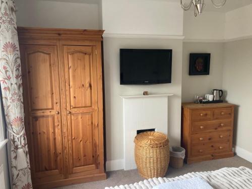 a living room with a television and a wooden cabinet at ABI B&B in Kent