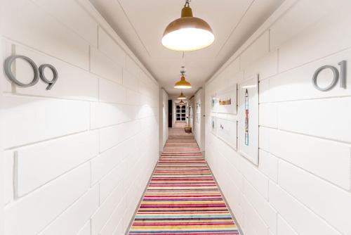 a hallway with white walls and a colorful rug on the floor at The Port Hotel in Visakhapatnam