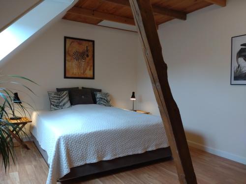 a bedroom with a white bed in a attic at Akaciegaarden Bed & Breakfast in Hårlev
