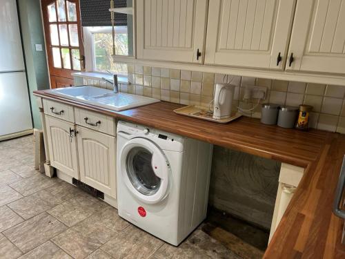 eine Küche mit einer Waschmaschine unter der Theke in der Unterkunft Antic Cottage for Family in Nottingham