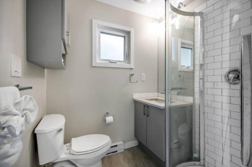 a white bathroom with a toilet and a shower at Family-friendly Cottage with amazing views in West Kelowna