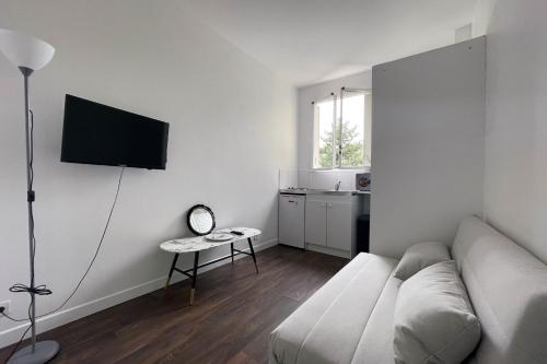 ein Wohnzimmer mit einem Sofa und einem TV an der Wand in der Unterkunft Neuilly sSeine - Inkermann in Neuilly-sur-Seine
