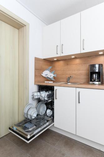 a kitchen with white cabinets and a dishwasher at Haus Strandkorb mit Frühstücksoption in Bensersiel