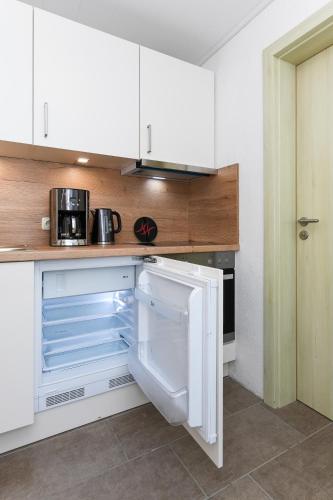 a white kitchen with an empty refrigerator in it at Haus Strandkorb mit Frühstücksoption in Bensersiel