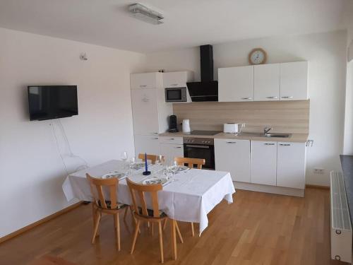 eine Küche mit einem Tisch mit Stühlen und einem weißen Tischtuch in der Unterkunft Ferienwohnung mit Neckarblick in Eberbach