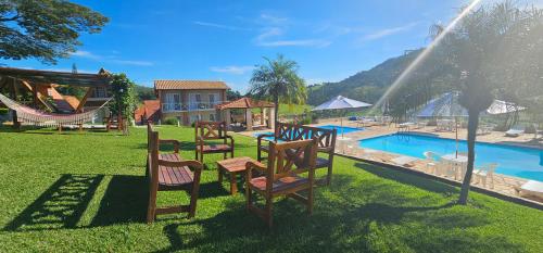 un grupo de sillas sentadas en el césped cerca de una piscina en Filimahalo Hotel, en Serra Negra