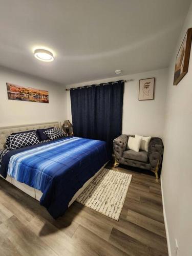 a bedroom with a blue bed and a chair at Cozy one bedroom in Airdrie in Airdrie