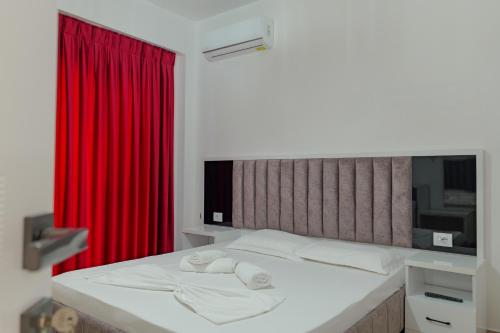 1 dormitorio con 1 cama con cortina roja en Hotel Take, en Borsh