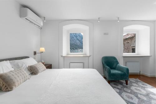 una camera bianca con un letto e una sedia verde di Casa Spada by Belsize a Kotor (Cattaro)