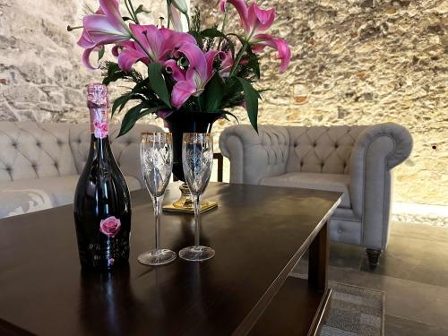 a table with a bottle of wine and two glasses and flowers at HOTEL BOUTIQUE CASONA 65 in Puebla