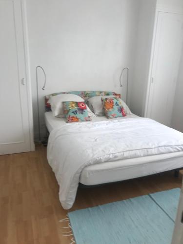 een bed met witte lakens en kussens in een kamer bij vacances in Urrugne