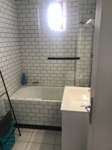 a white bathroom with a tub and a sink at vacances in Urrugne