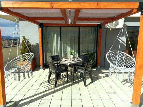 eine Terrasse mit einem Tisch und Stühlen auf dem Balkon in der Unterkunft Penthouse City View Infinity in Braşov