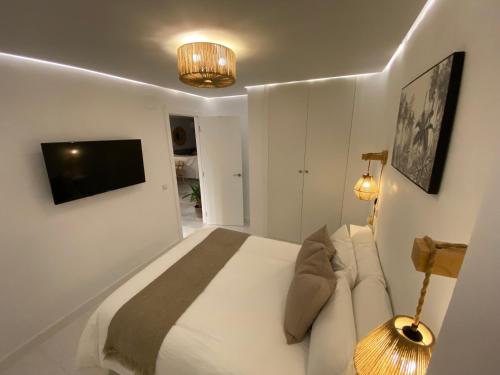 ein Schlafzimmer mit einem Bett und einem TV an der Wand in der Unterkunft La Cala Beach Home in La Cala del Moral