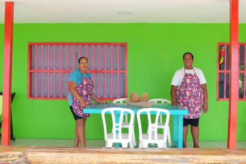 two women standing in a green room with a table and chairs at Cabaña en primera línea de playa en San Antero con Aire AC y 5 habitaciones in San Antero