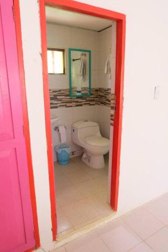 a bathroom with a toilet and a pink door at Cabaña en primera línea de playa en San Antero con Aire AC y 5 habitaciones in San Antero