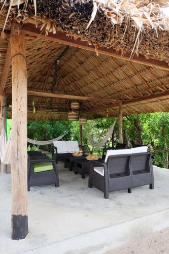 a group of tables and chairs under a straw roof at Cabaña en primera línea de playa en San Antero con Aire AC y 5 habitaciones in San Antero