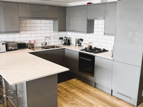 una cocina con electrodomésticos blancos y armarios grises en 25 Breakwaters - Pet friendly, en Sandown